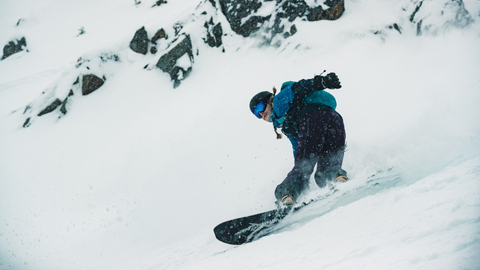 Snowboarder sprays snow on a cloudy powder day