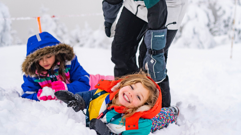 two children play in the snow with their mom. 