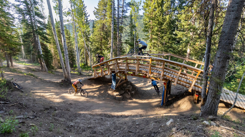 Mountain bikers ride over a wooden bridge feature on Cobalt Cruise at Solitude Bike Park.