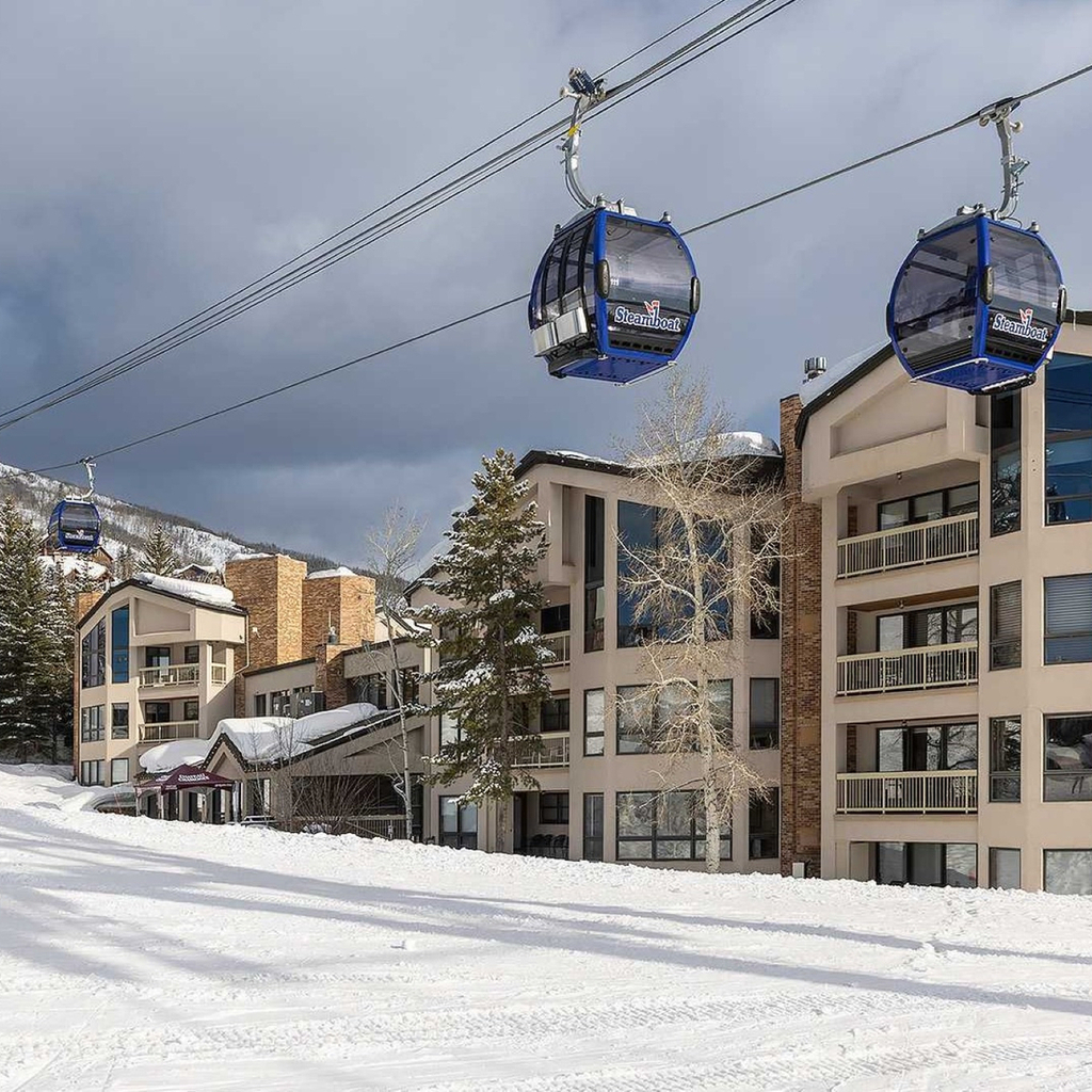 A snowy exterior view of a building with gondola lifts in the foreground.