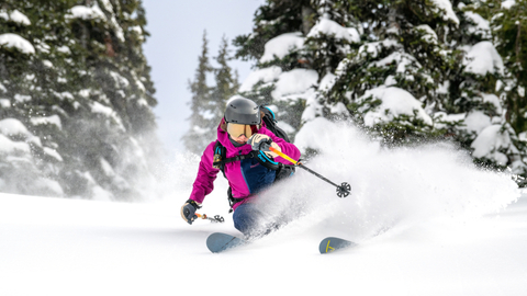Skier shreds powder with a cloudy background.