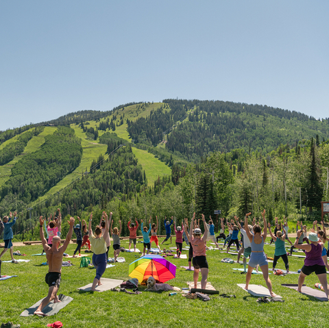 People doing yoga in the sun outside overlooking the ski slopes