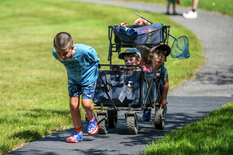 kids in a wagon walking to do activities at stratton resort during a sunny afternoon, enjoying outdoor activities as part of the summer camp for kids