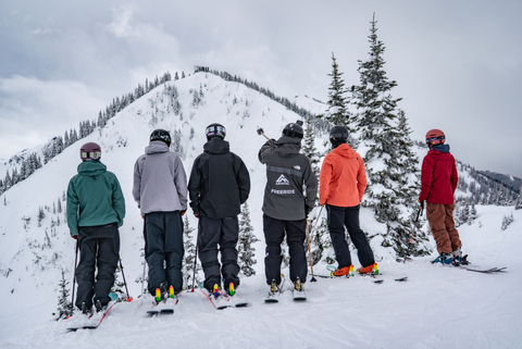 Crystal Freeride group stands on the ridge of a mountain looking down. 