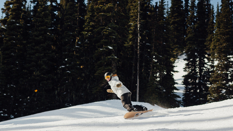 Snowboarder turns on a groomer during a bluebird day. 