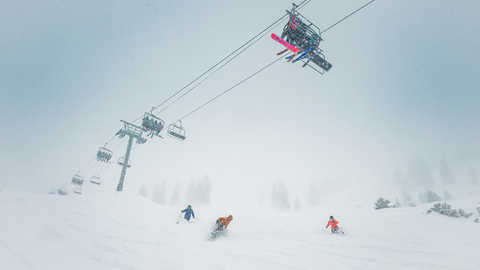 Friends skis on a powder day under the lift at Solitude Mountain Resort. 