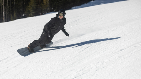 Snowboarder turns on a groomer.