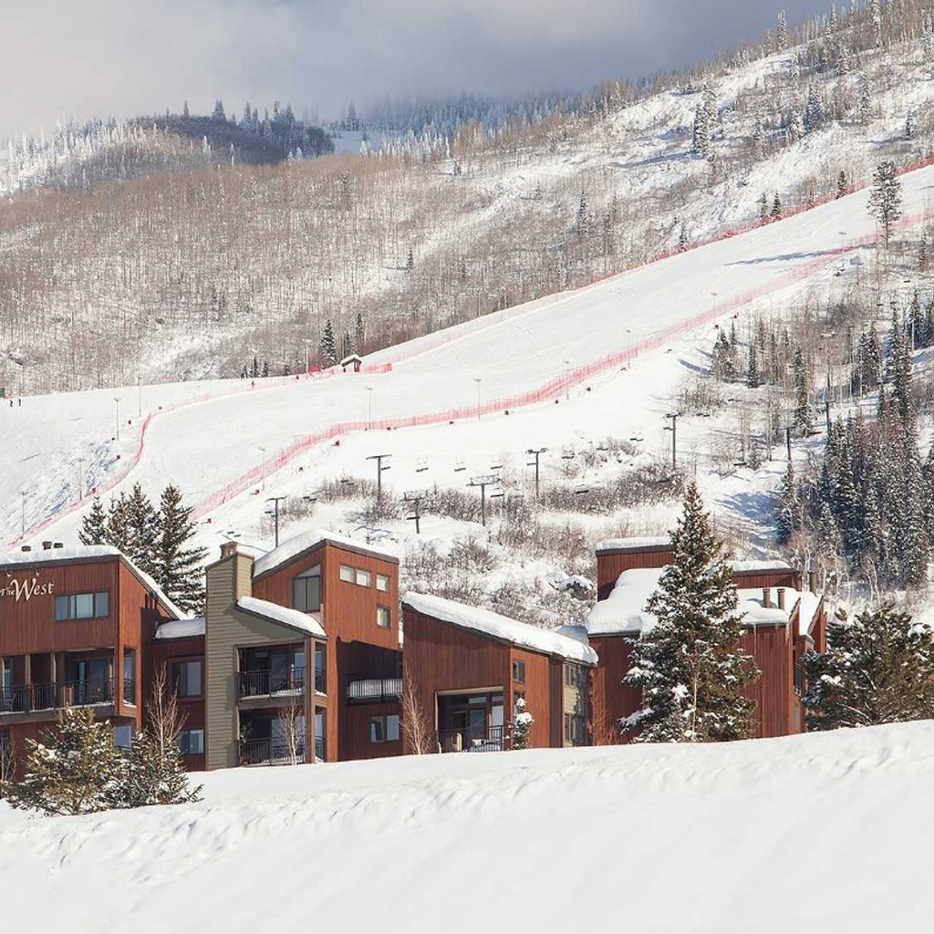 A snowy mountain with ski slopes and buildings at the base.