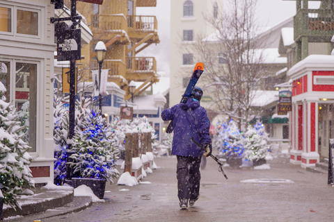 skier walking through a winter village during holiday week schedule and events at stratton
