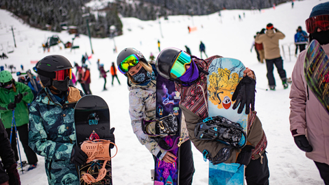 three snowboarders in a lift line