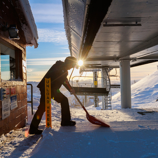 Liftie at Crystal Mountain shovels the platform at sunrise. 