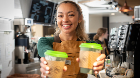 Brew 62 Employee hands a Coffee Across the Counter