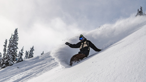 Snowboarder sprays snow on a heel edge turn