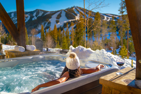 a woman wearing a white beanie hat sits in a hot tub in lodging at Winter Park Resort