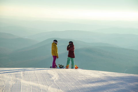 Two snowboard girls scenic view morning groomer carpet corduroy wide vista above clouds
