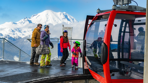 Family exits the scenic gondola with Mt. Rainier in the background.
