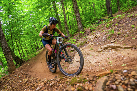A mountain biker riding uphill on a wooded bike trail at Stratton vermont