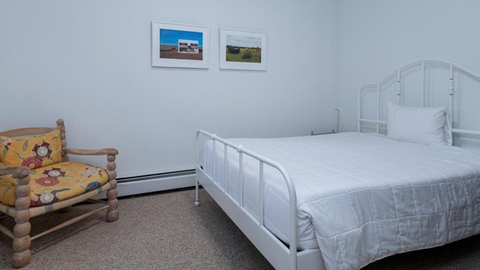 simple guest room with metal bed frame and playful accent chair at 19 middle ridge vacation rental