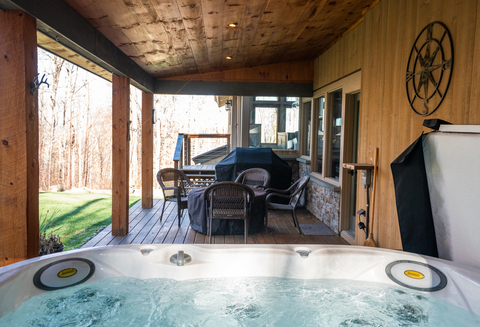 covered deck with dining space and bubbling hot tub at 34 saw milla vacation rental at stratton resort
