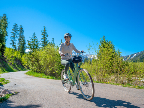 a woman rides an e-bike on the Fraser River Trail near Winter Park Resort