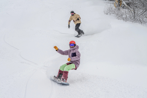 two snowboarders riding down the mountain at a snowboard week lesson